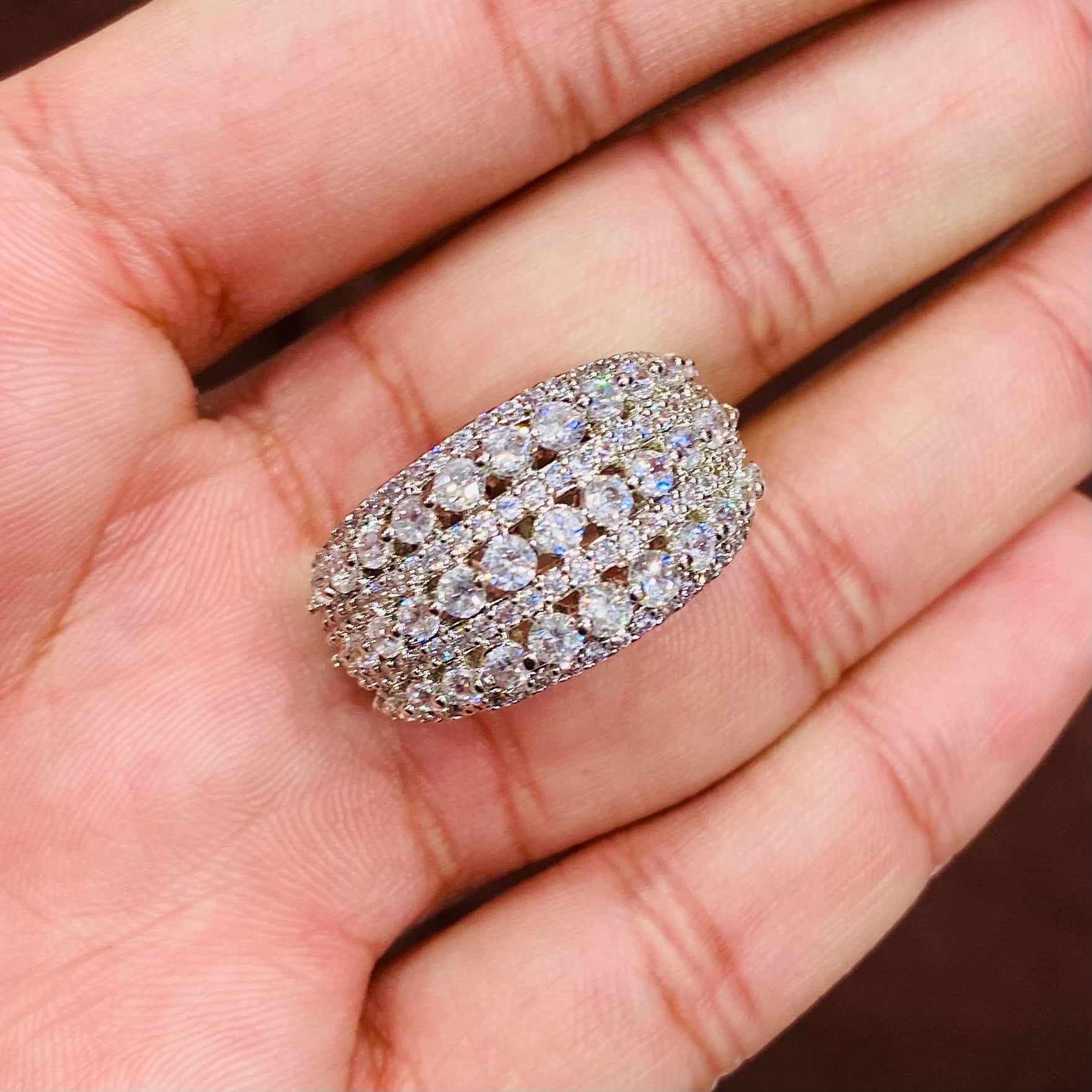 Silver ring with multiple diamonds held in a hand