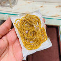 Gold chain on a white paper towel held by a hand with a blurred background