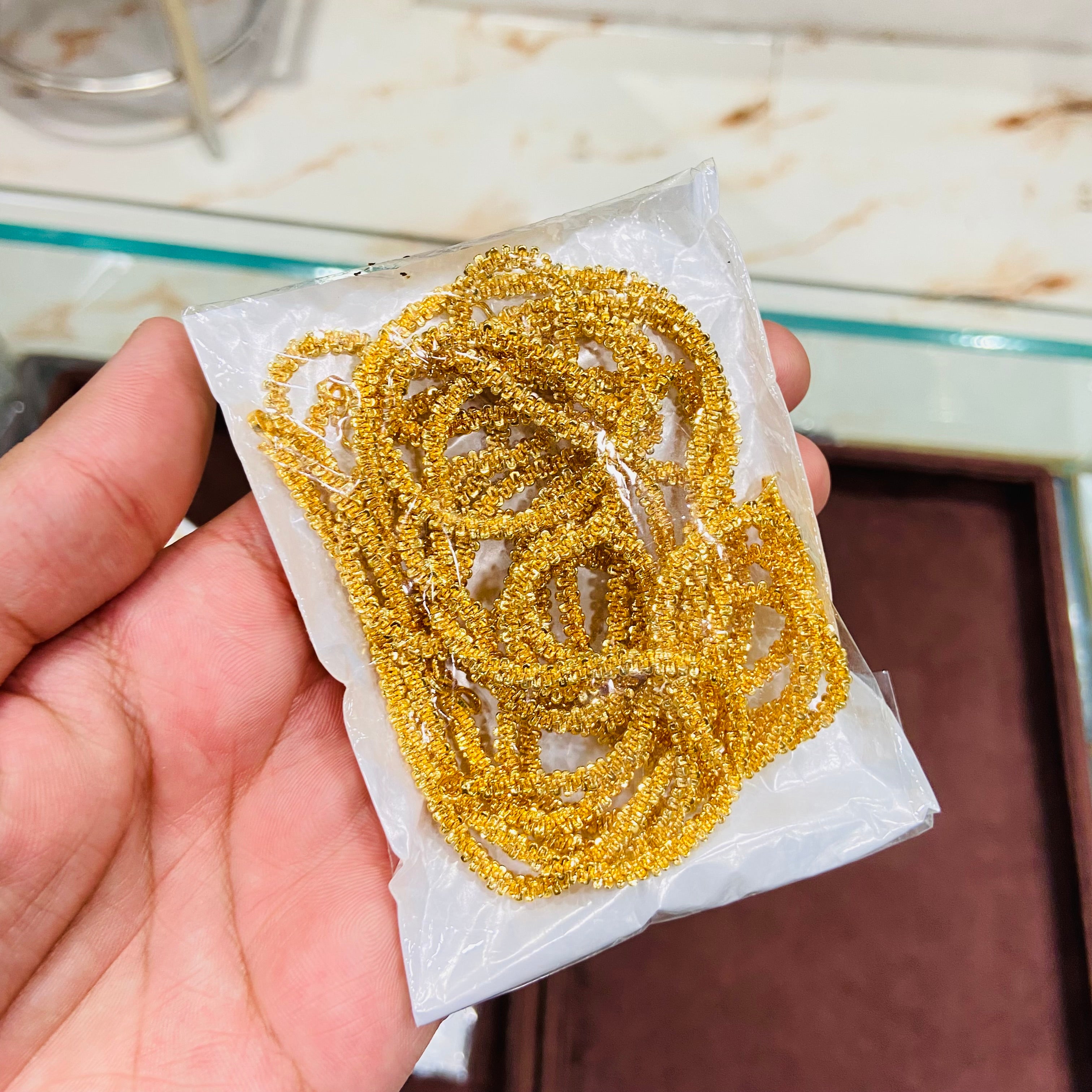Gold chain on a white paper towel held by a hand with a blurred background