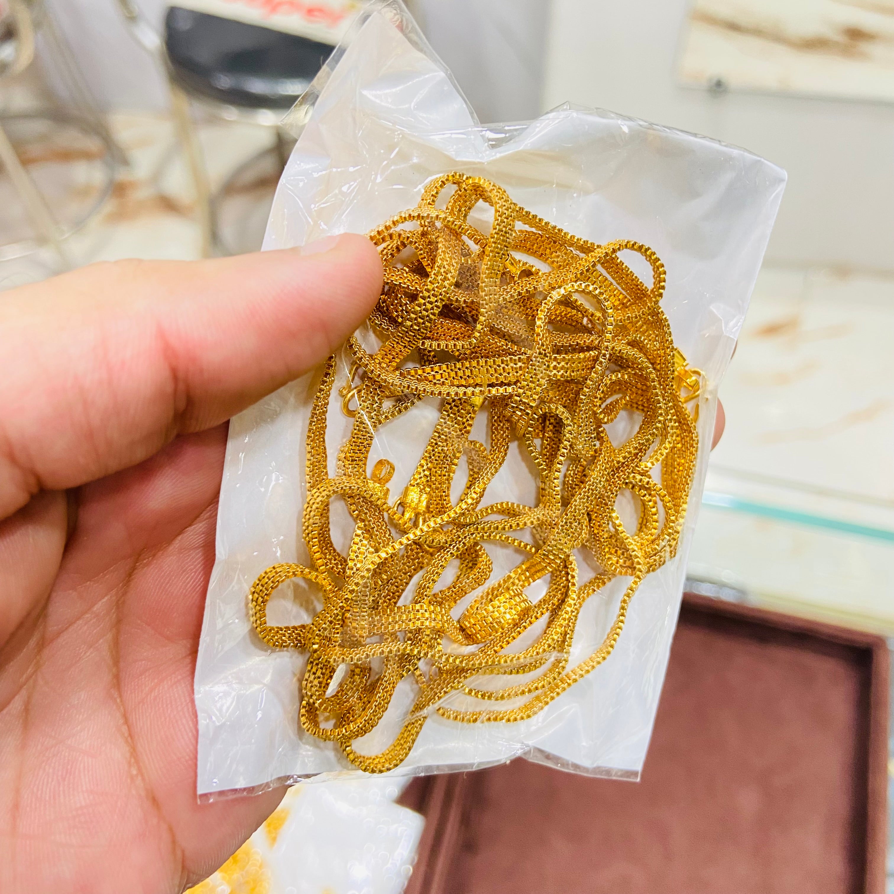 Gold chains on a white paper held by a hand with a blurred background