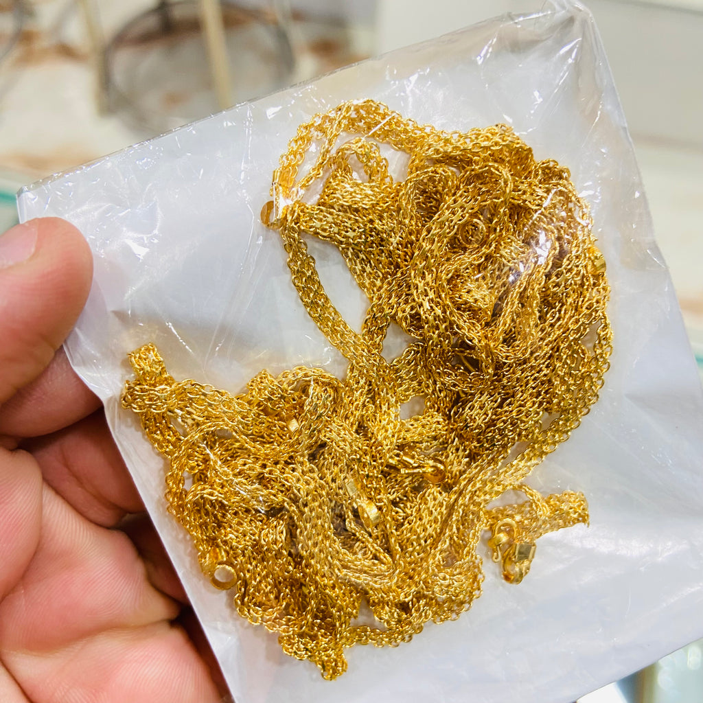 Gold chain held over a white paper background
