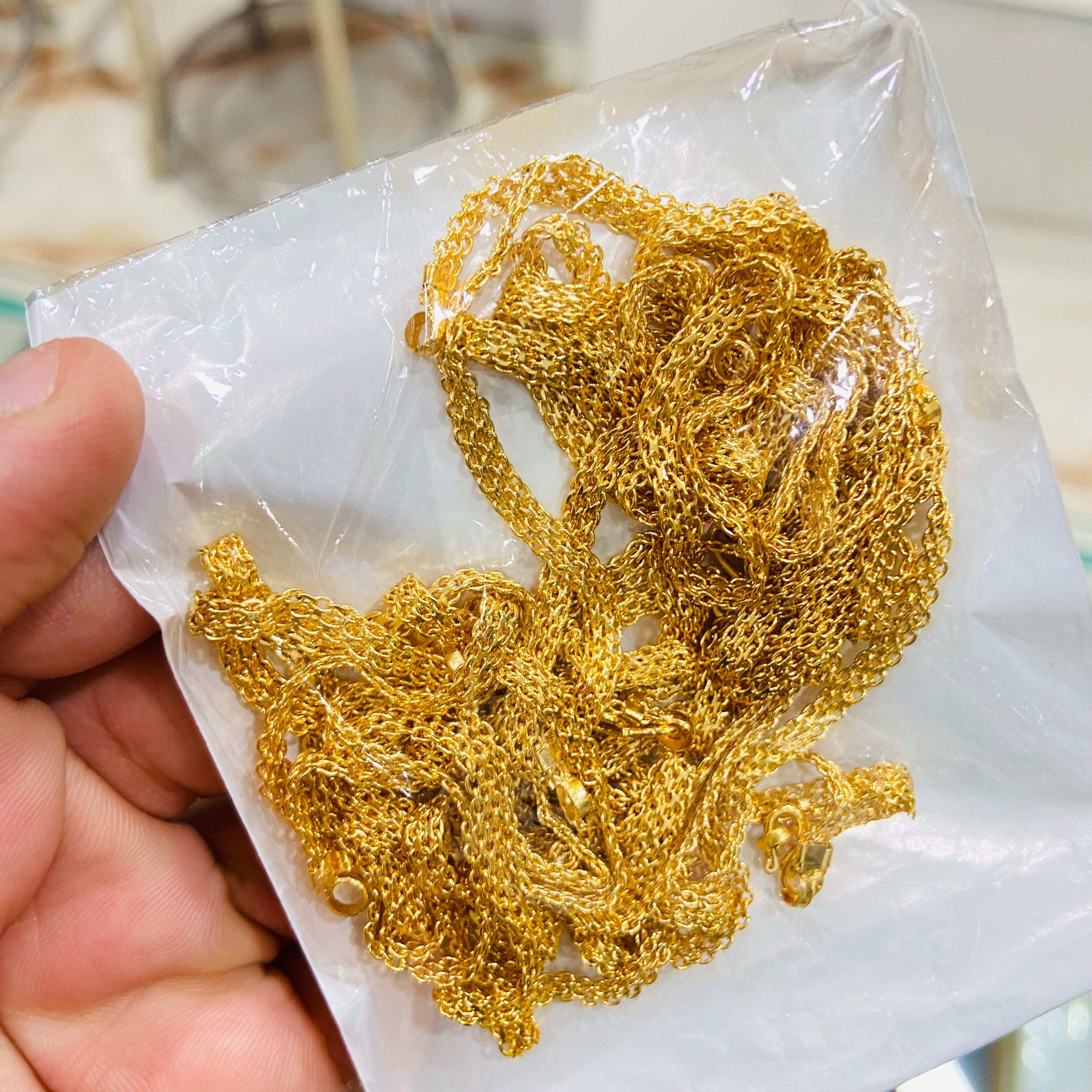 Gold chain held over a white paper background