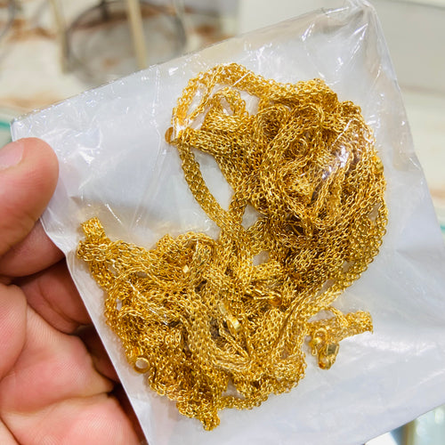 Gold chain held over a white paper background