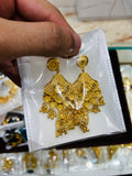 Gold earrings on a white card held by a hand with a blurred background