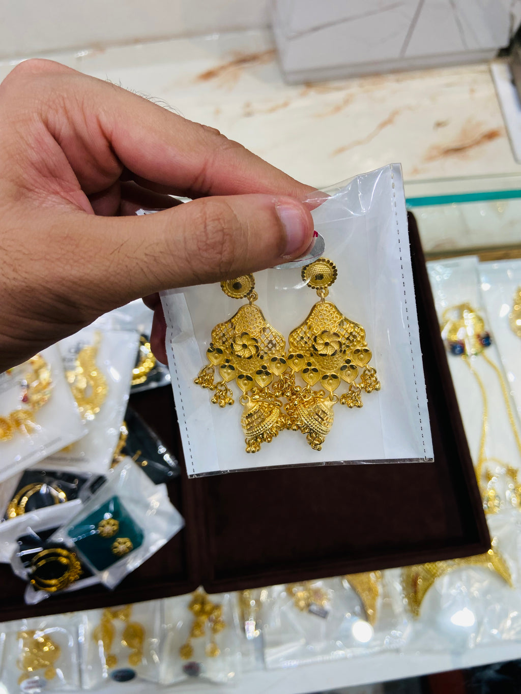 Gold earrings on a display card held by a hand with a blurred background
