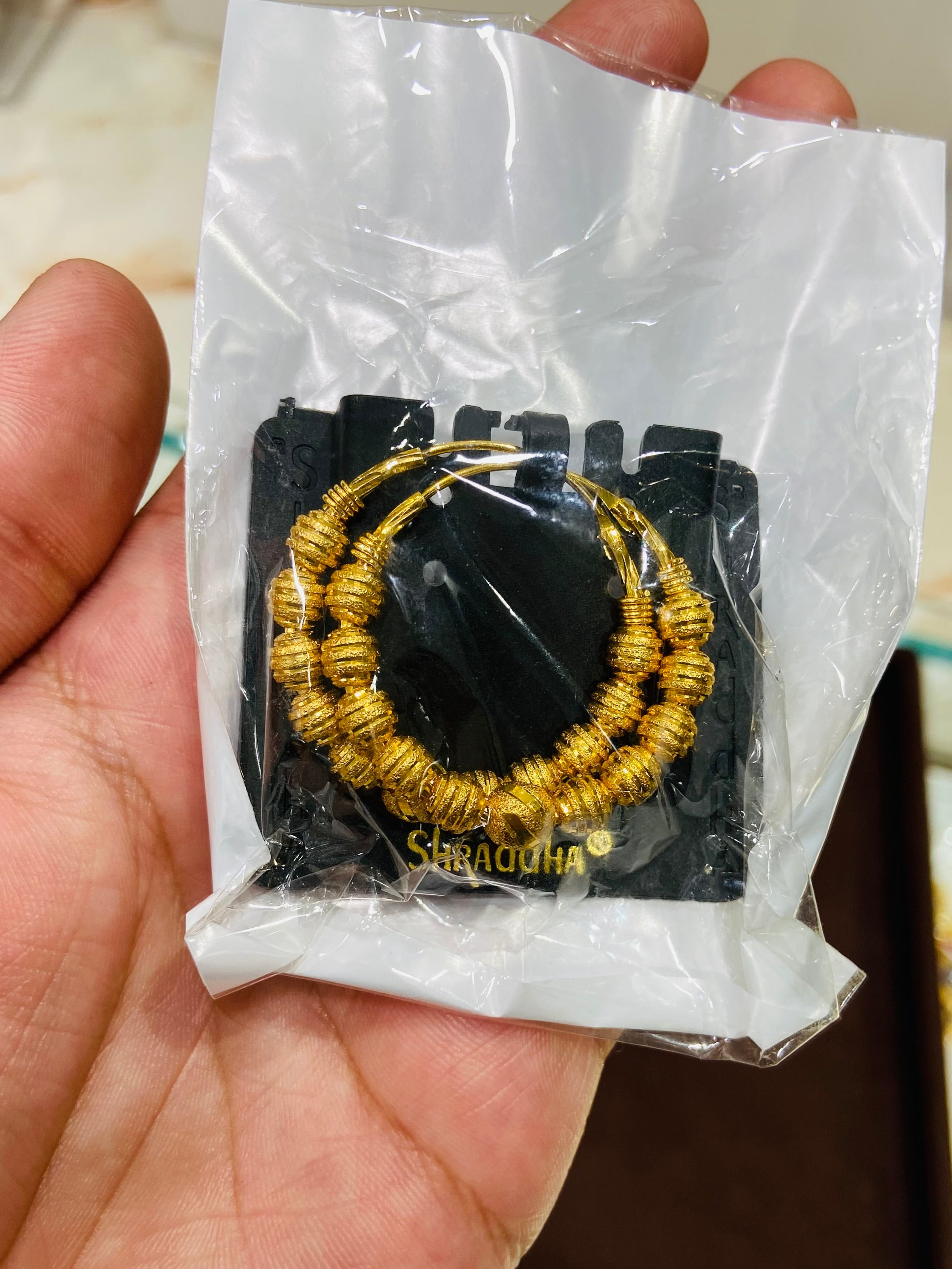 Gold earrings ties in a clear plastic bag held by a hand