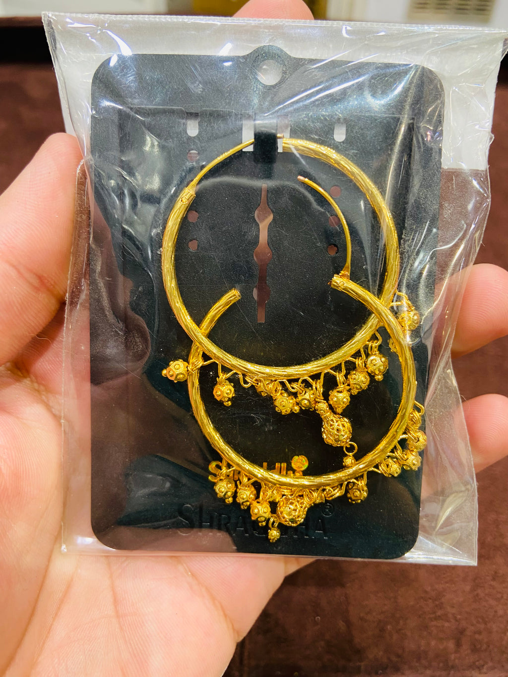 Gold earrings in packaging held by a hand