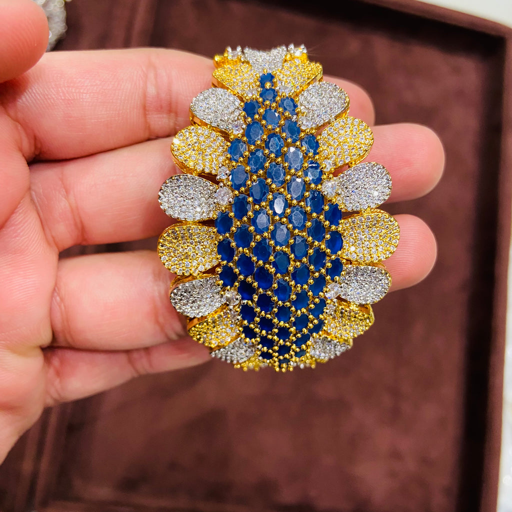 Close-up of a hand holding a decorative bracelet with blue, yellow, and silver stones.