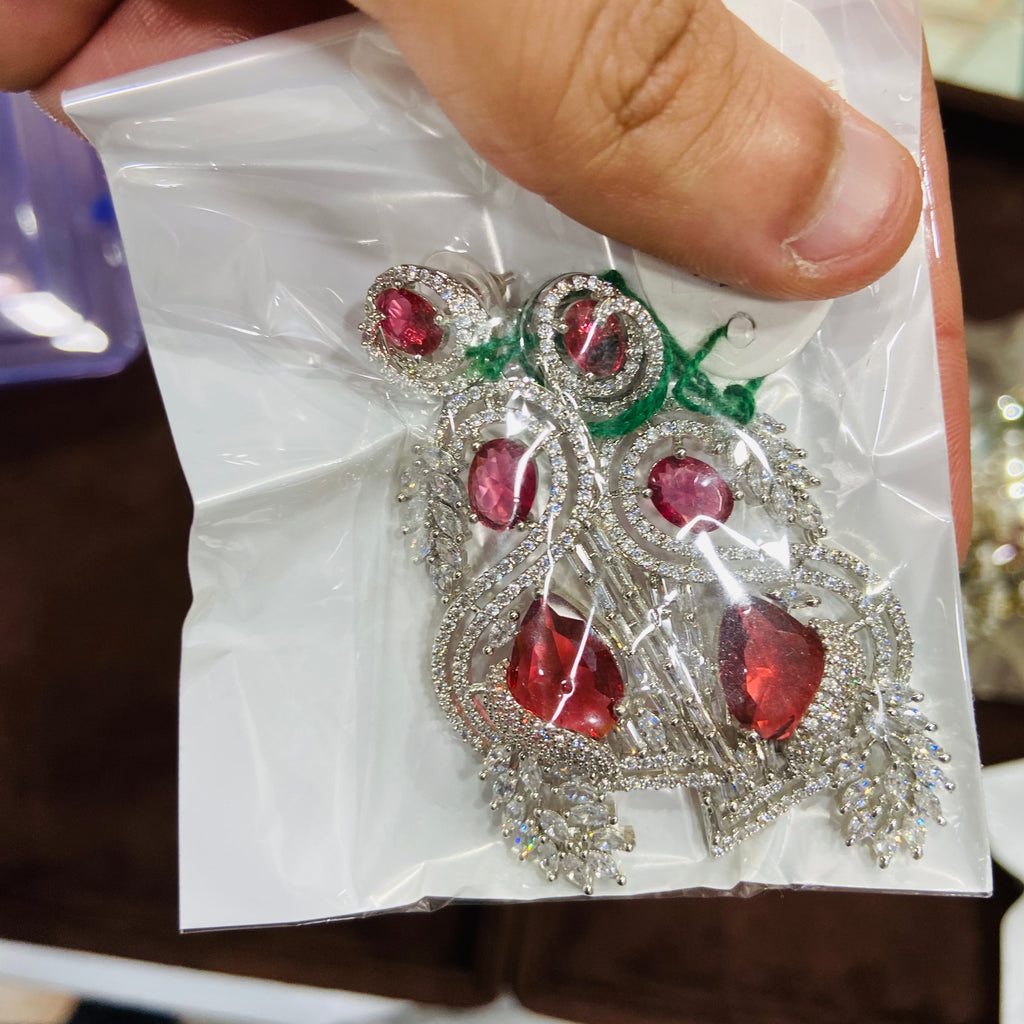Earrings with red gemstones and silver accents on a white paper background