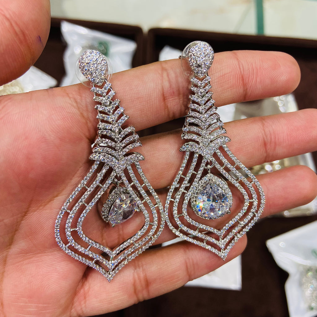 Silver earrings with gemstones held in a hand