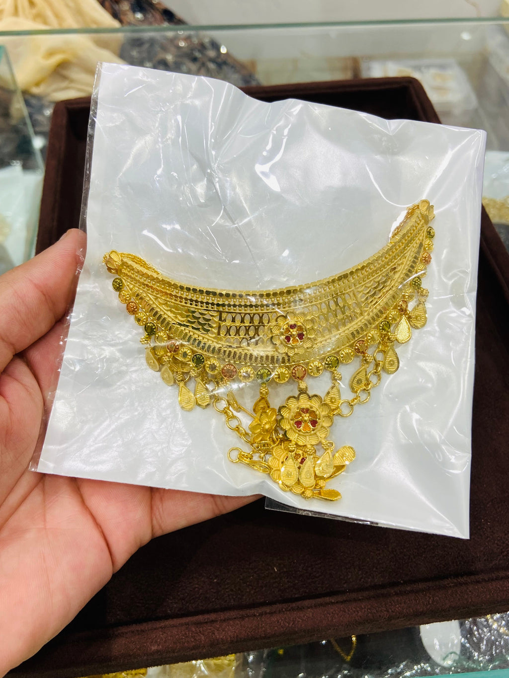 Gold necklace on a white card held by a hand with a blurred background