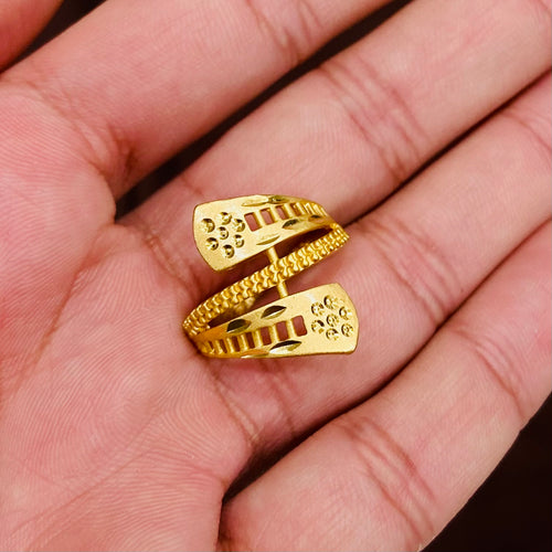 Gold ring with intricate design held in a hand