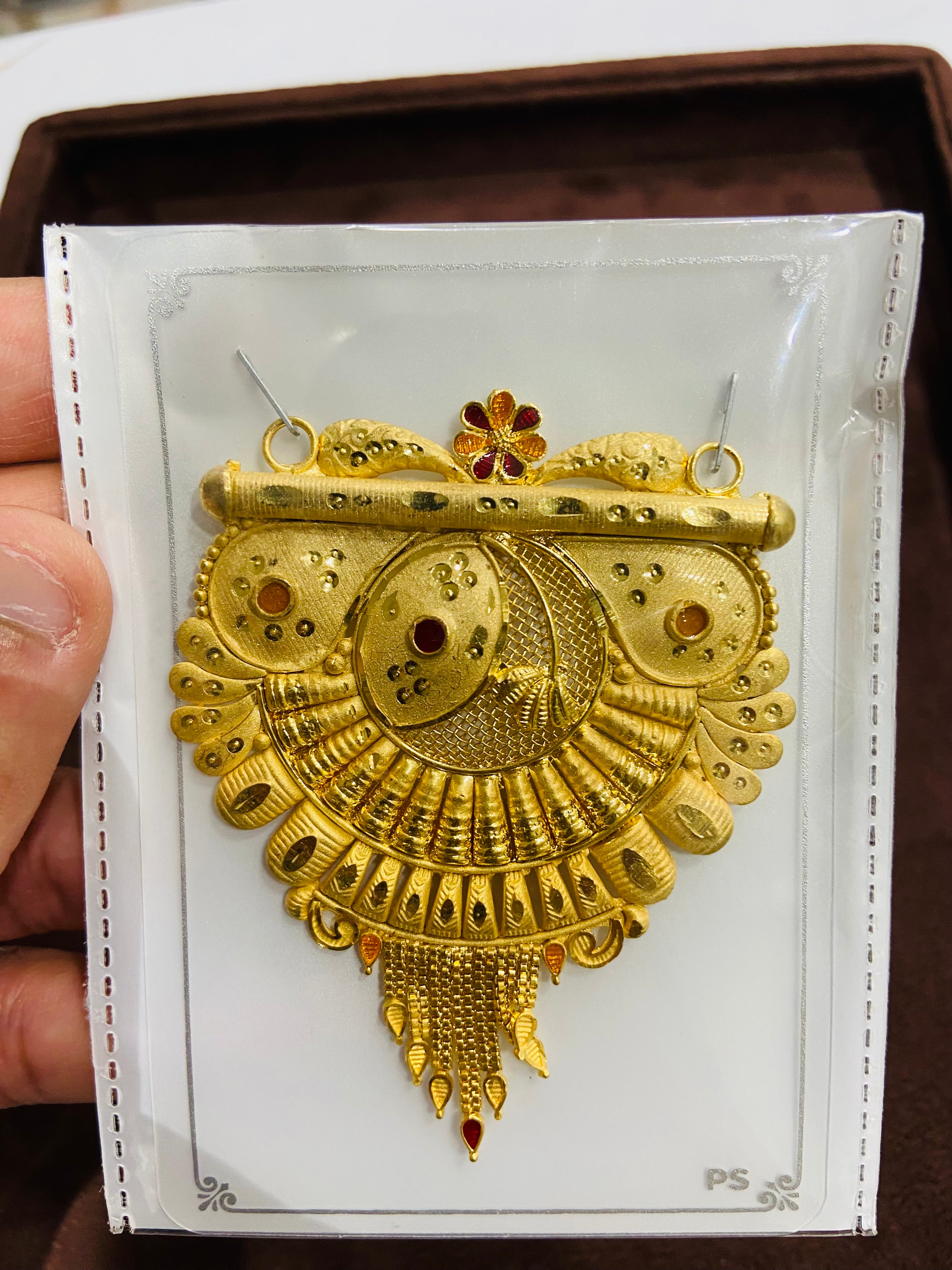 Gold pendant on a white card held by a hand