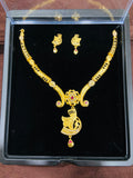 Gold necklace and earrings set in a clear display case on a dark background