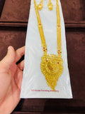 Gold necklace on a white card with text, held by a hand against a brown background