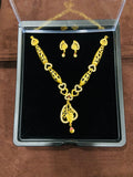 Gold necklace and earrings set in a clear display case on a brown surface.