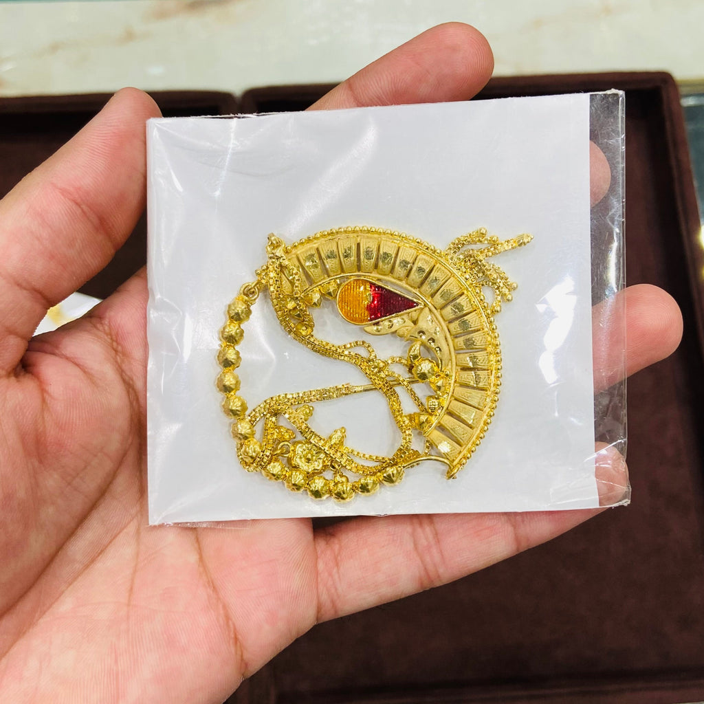 Gold dragon nath on a white card held by a hand with a blurred background