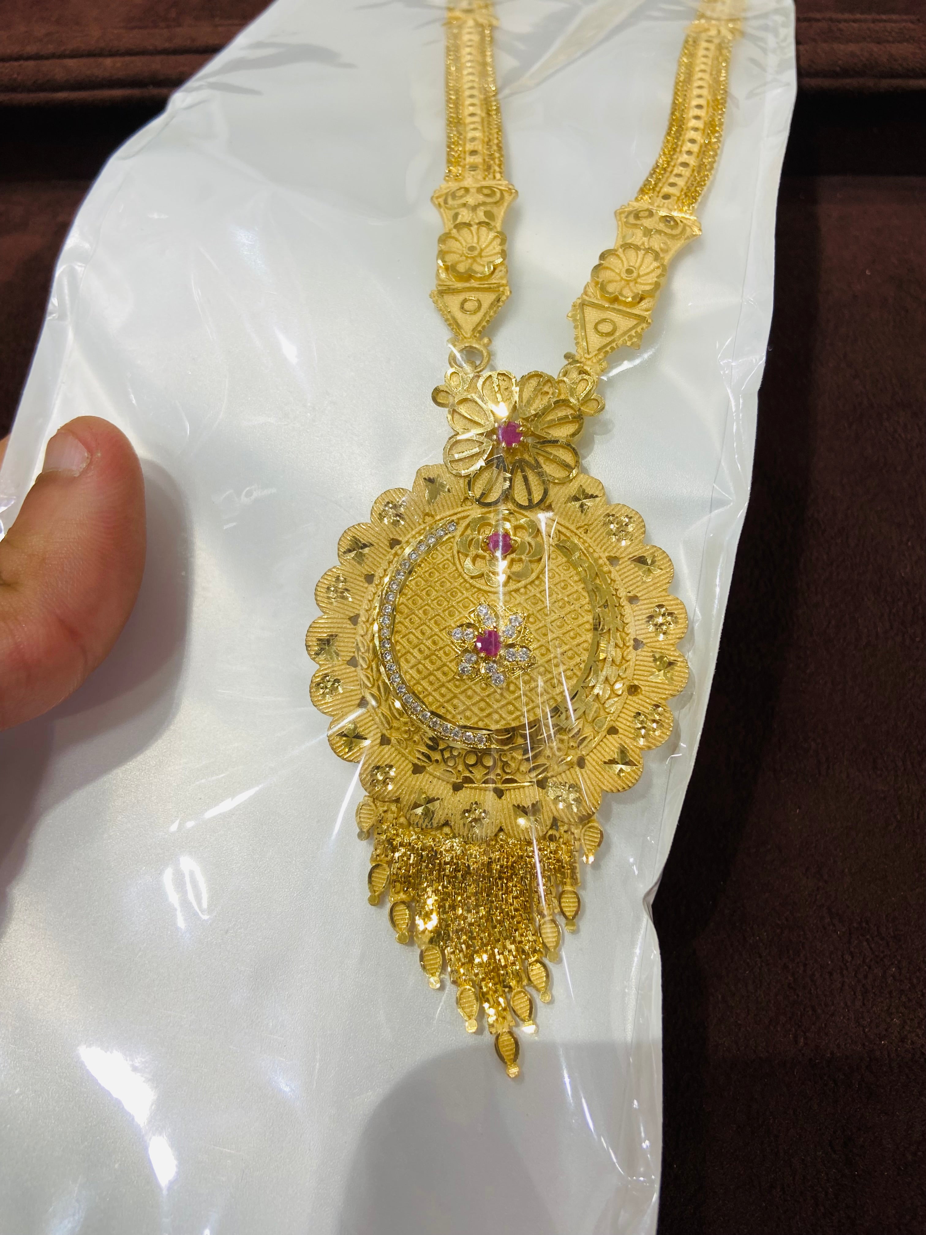 Gold necklace with intricate design on a white surface