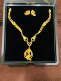 Gold necklace and earrings set in a black display box on a wooden surface