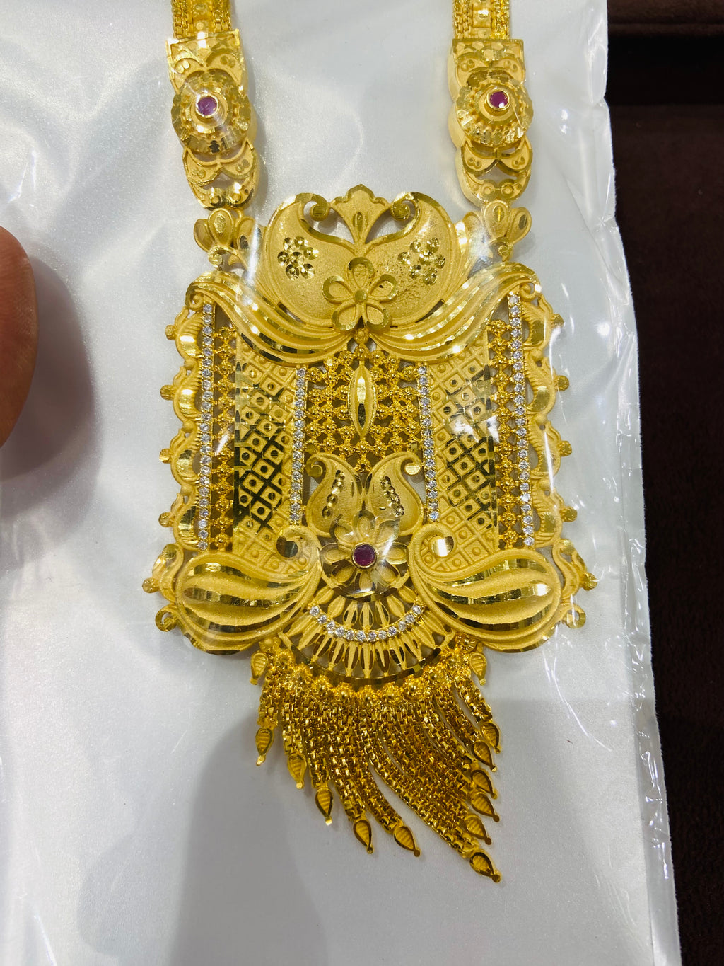 Gold necklace with intricate designs on a white background