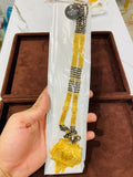 Gold necklace with black beads held by a hand against a brown jewelry box background