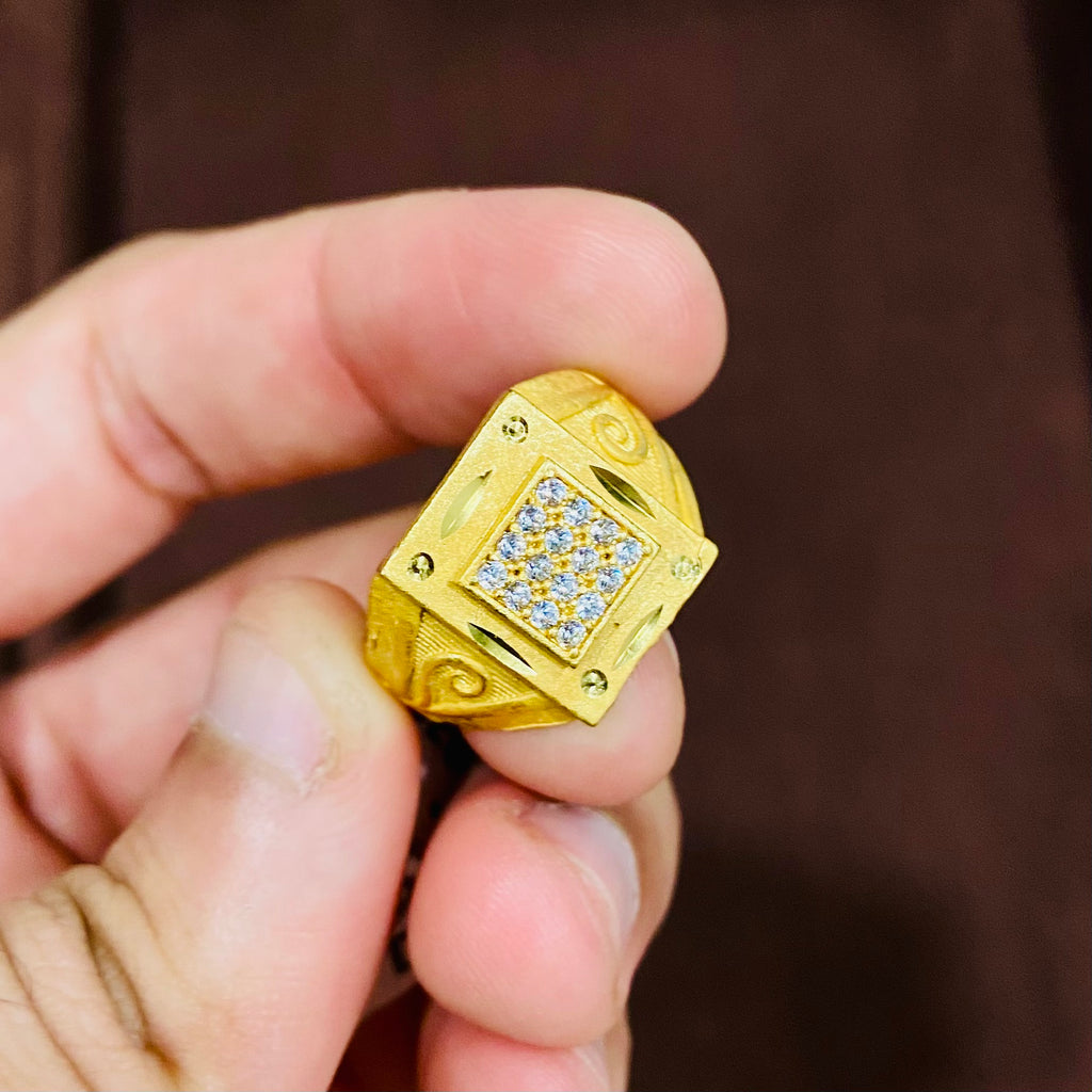 Gold ring with diamond accents held in a hand against a blurred background
