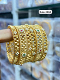 Gold bangles with gemstones on a blurred background
