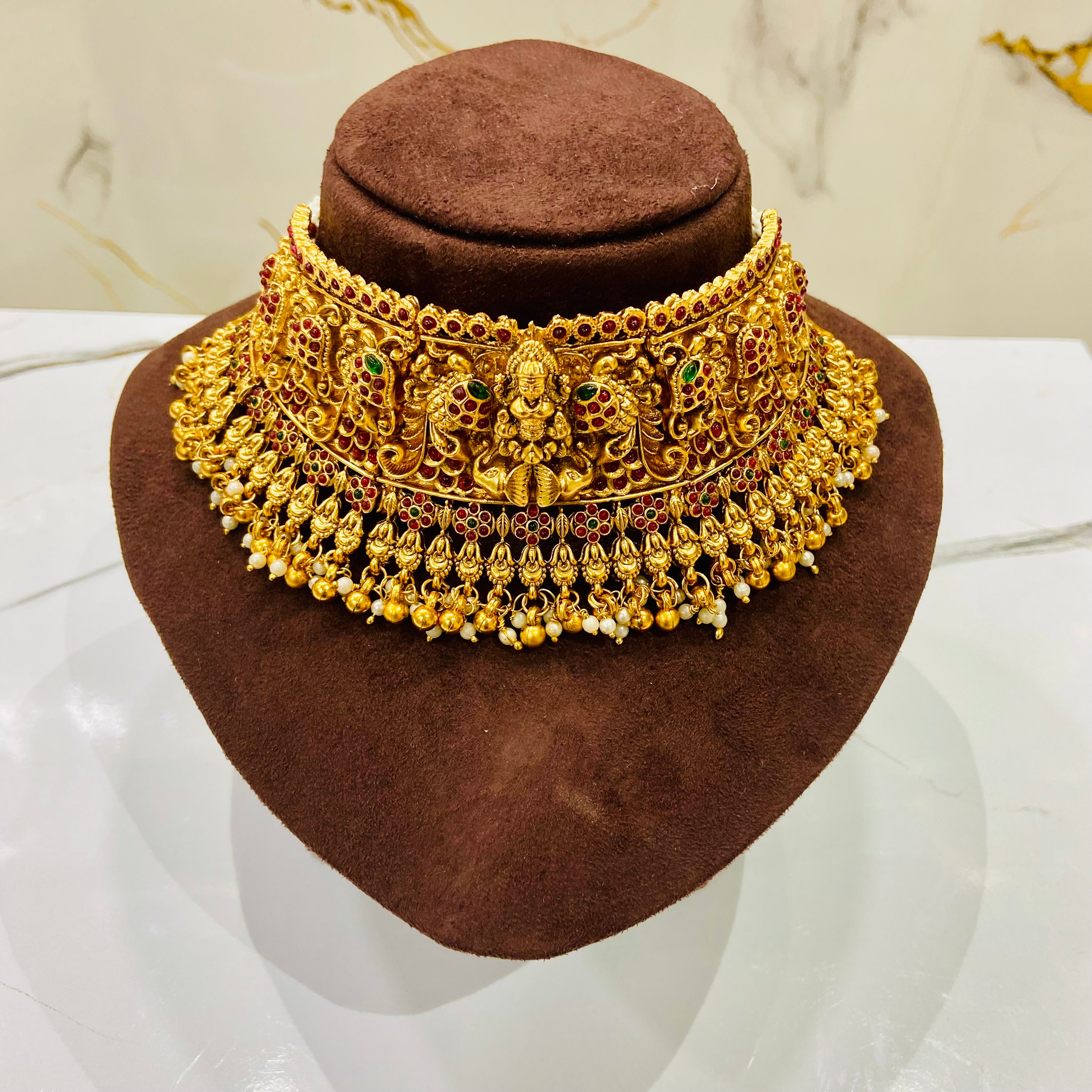 Gold necklace on a brown mannequin head with a marble background